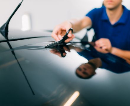 Male worker with scissors, car tinting film installation process, tinted auto glass installing procedure
